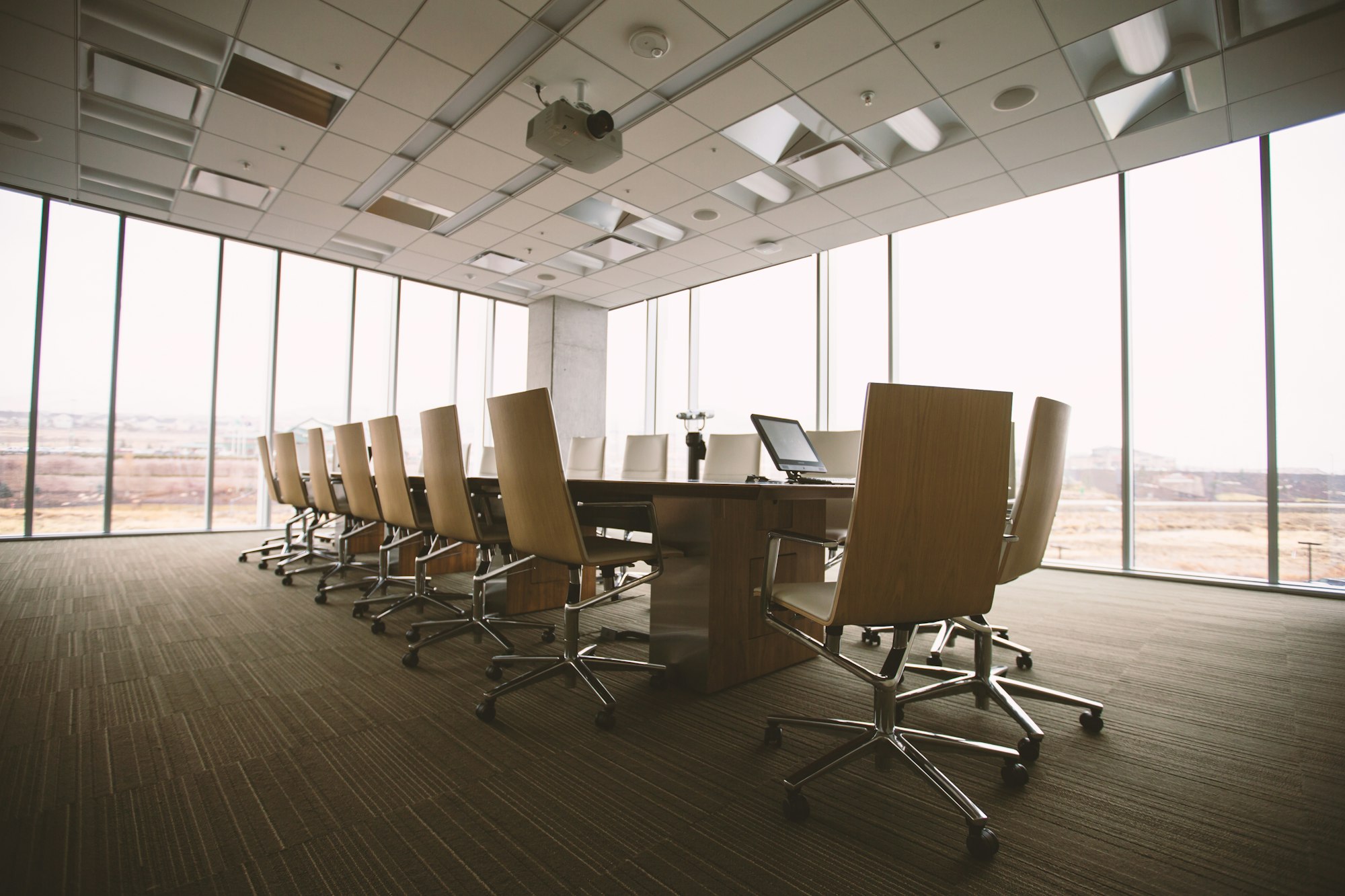 An empty boardroom table in a sunlit conference room